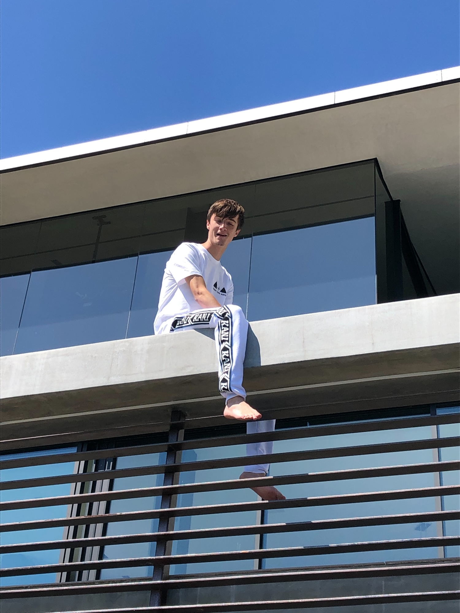 Johnny sitting on a ledge against an open sky
